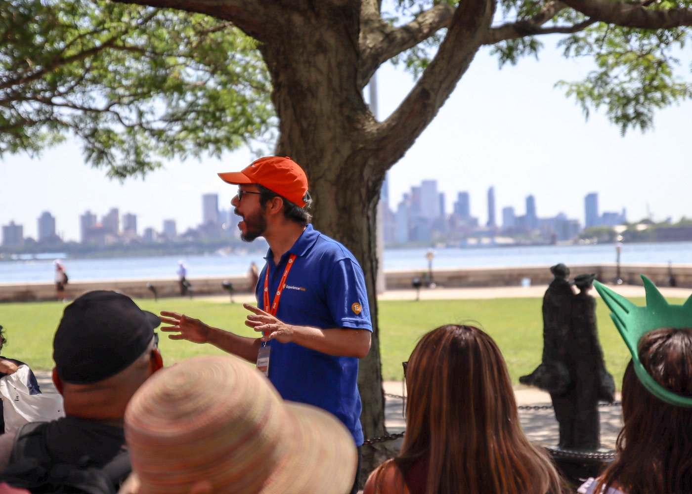 Tourguide bei einer Führung auf Liberty Island mit Blick auf die Skyline von New York