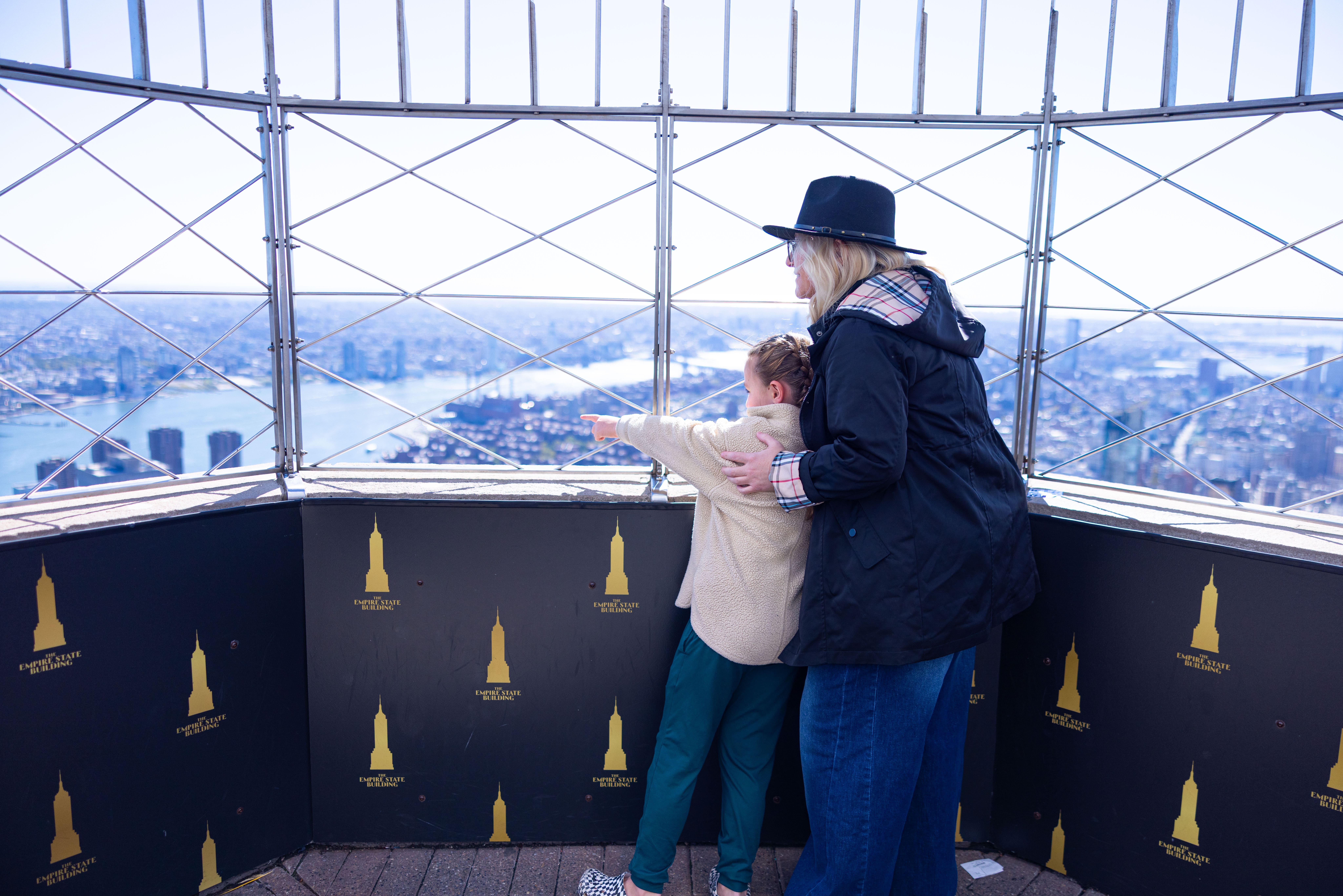 Mutter und Kind blicken von der Aussichtsplattform des Empire State Buildings über New York