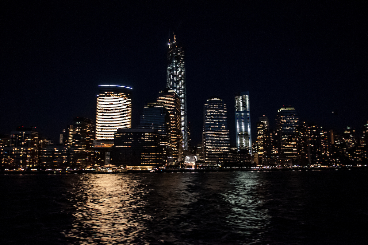 Beleuchtete Skyline von Lower Manhattan bei Nacht vom Hudson River aus