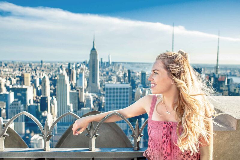 Junge Frau genießt den Panoramablick vom Top of the Rock auf die Skyline von New York mit dem Empire State Building.