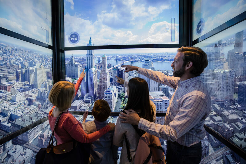 Familie genießt die Aussicht auf Manhattan und die New Yorker Skyline von einer verglasten Aussichtsplattform.