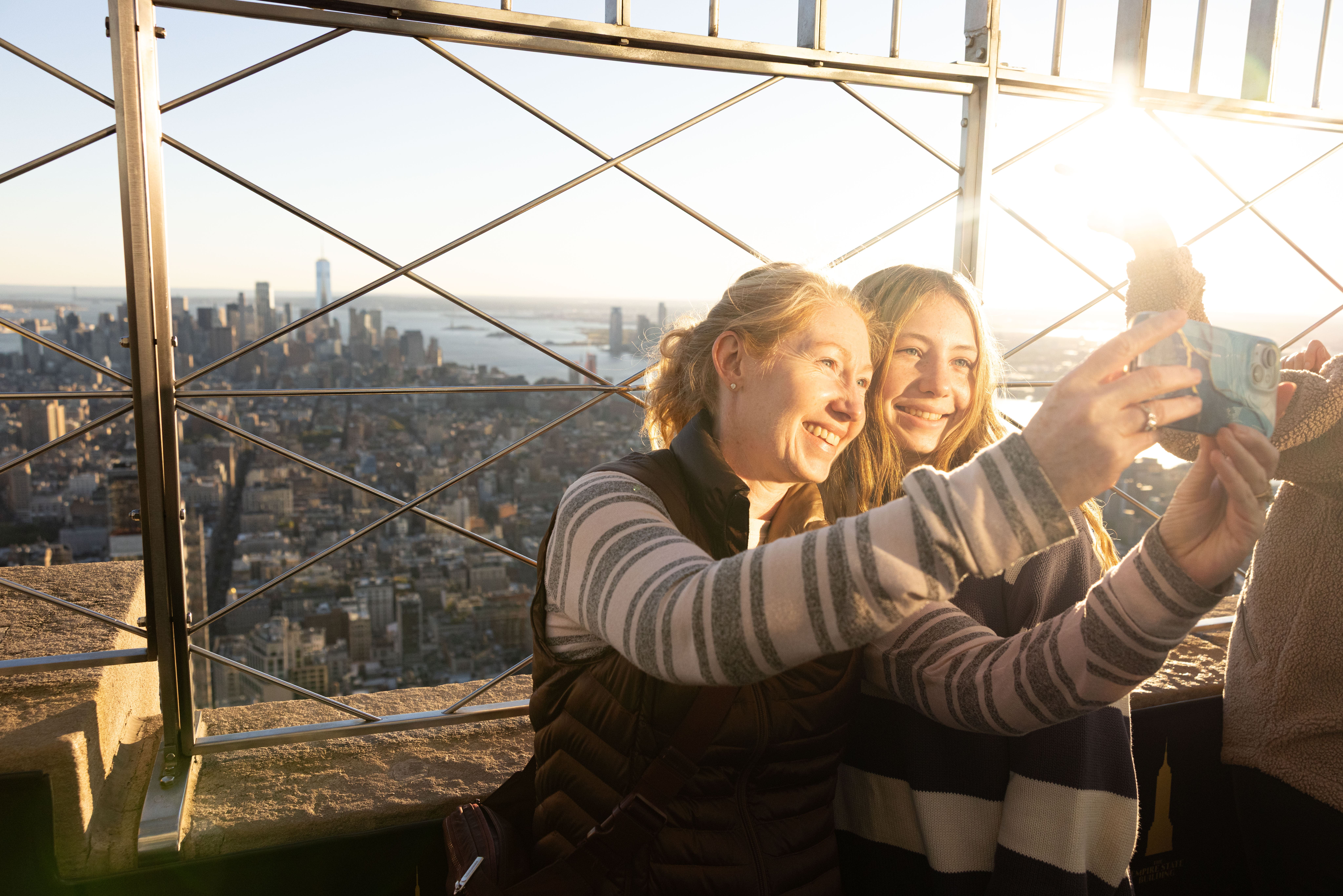 Mutter und Tochter machen ein Selfie auf der Aussichtsplattform des Empire State Buildings bei Sonnenuntergang