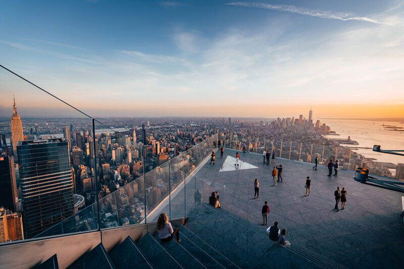 Outdoor-Aussichtsplattform Edge NYC mit Glasboden, Besuchern und beeindruckendem Blick über Manhattan bei Sonnenuntergang.