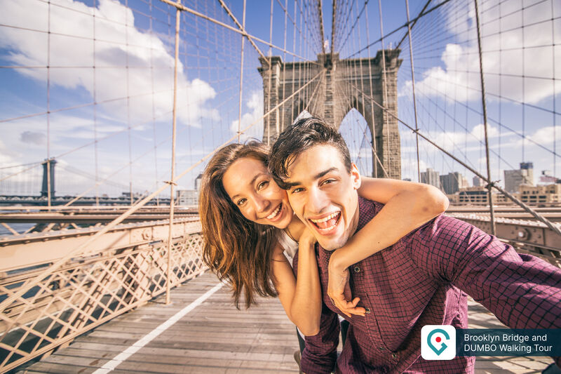 Junges Paar auf der Brooklyn Bridge während einer Sightseeing-Tour mit Blick auf die Brückenkonstruktion.