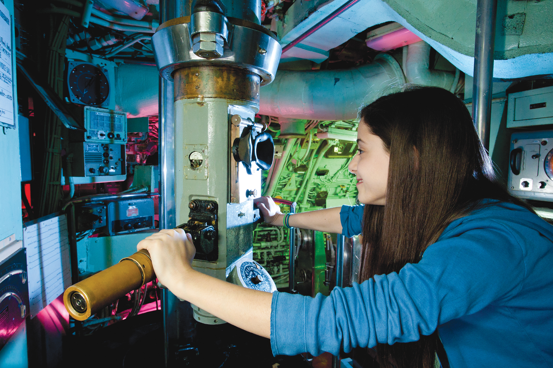 Besucherin bedient ein Periskop im historischen U-Boot des Intrepid Sea, Air & Space Museum in New York