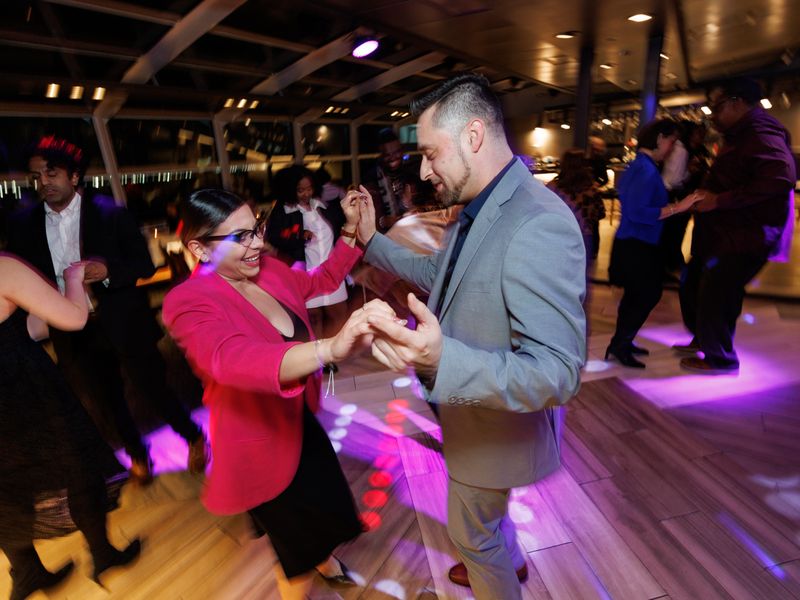 Gäste tanzen auf der beleuchteten Tanzfläche eines Ausflugsschiffes während einer abendlichen Dinner Cruise in New York.