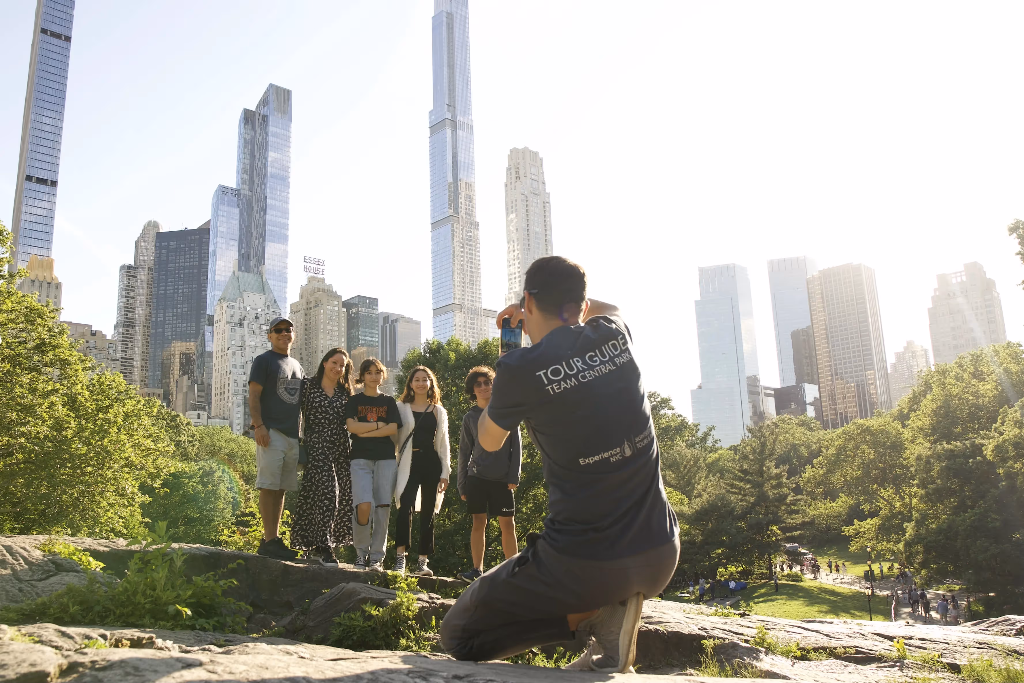 Tour Guide fotografiert Gruppe im Central Park vor der Skyline von Manhattan
