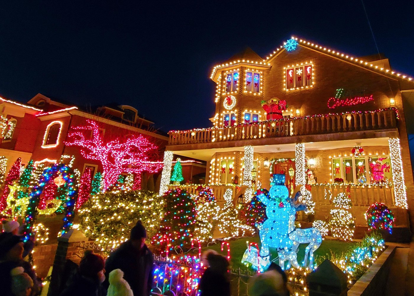 Festlich beleuchtetes Haus in Dyker Heights mit leuchtendem Schneemann, Rentierfiguren und bunten Weihnachtslichtern.