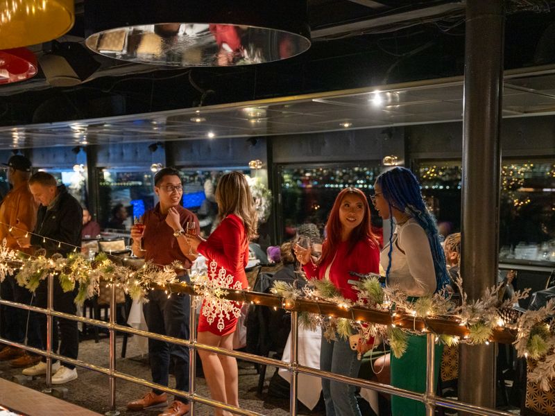 Gäste genießen Drinks und unterhalten sich auf einem festlich geschmückten Ausflugsschiff von City Cruises in New York.