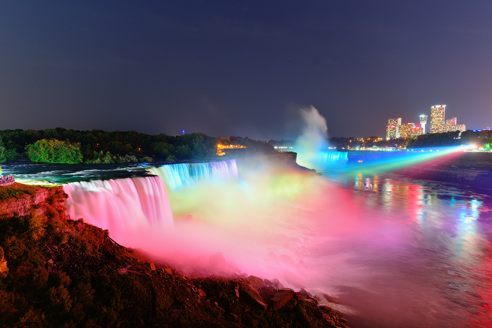 Farbenprächtig beleuchtete Niagarafälle bei Nacht mit Blick auf Niagara Falls in Kanada