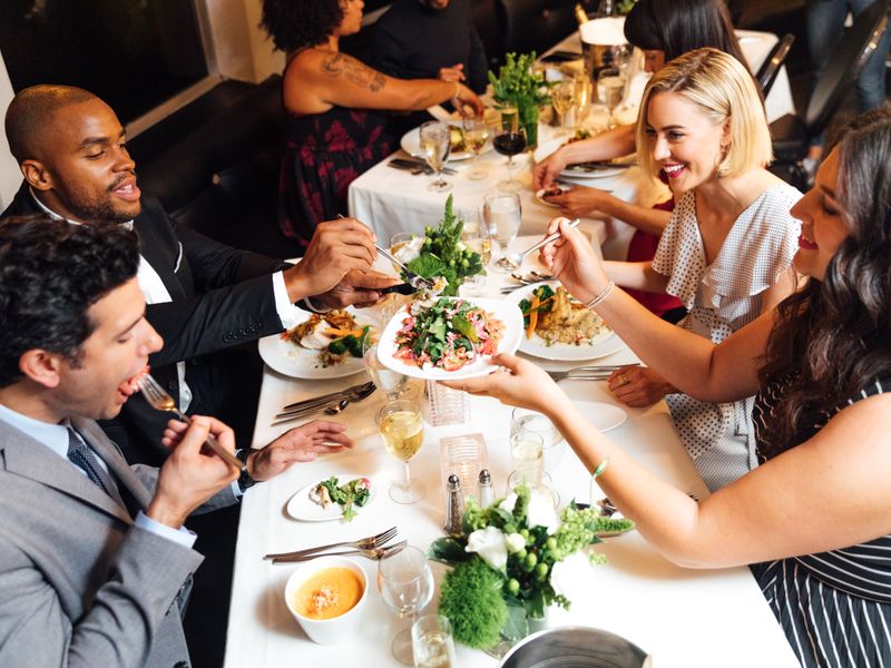 Gäste genießen ein mehrgängiges Abendessen an einem elegant gedeckten Tisch während einer Dinner Cruise in New York.