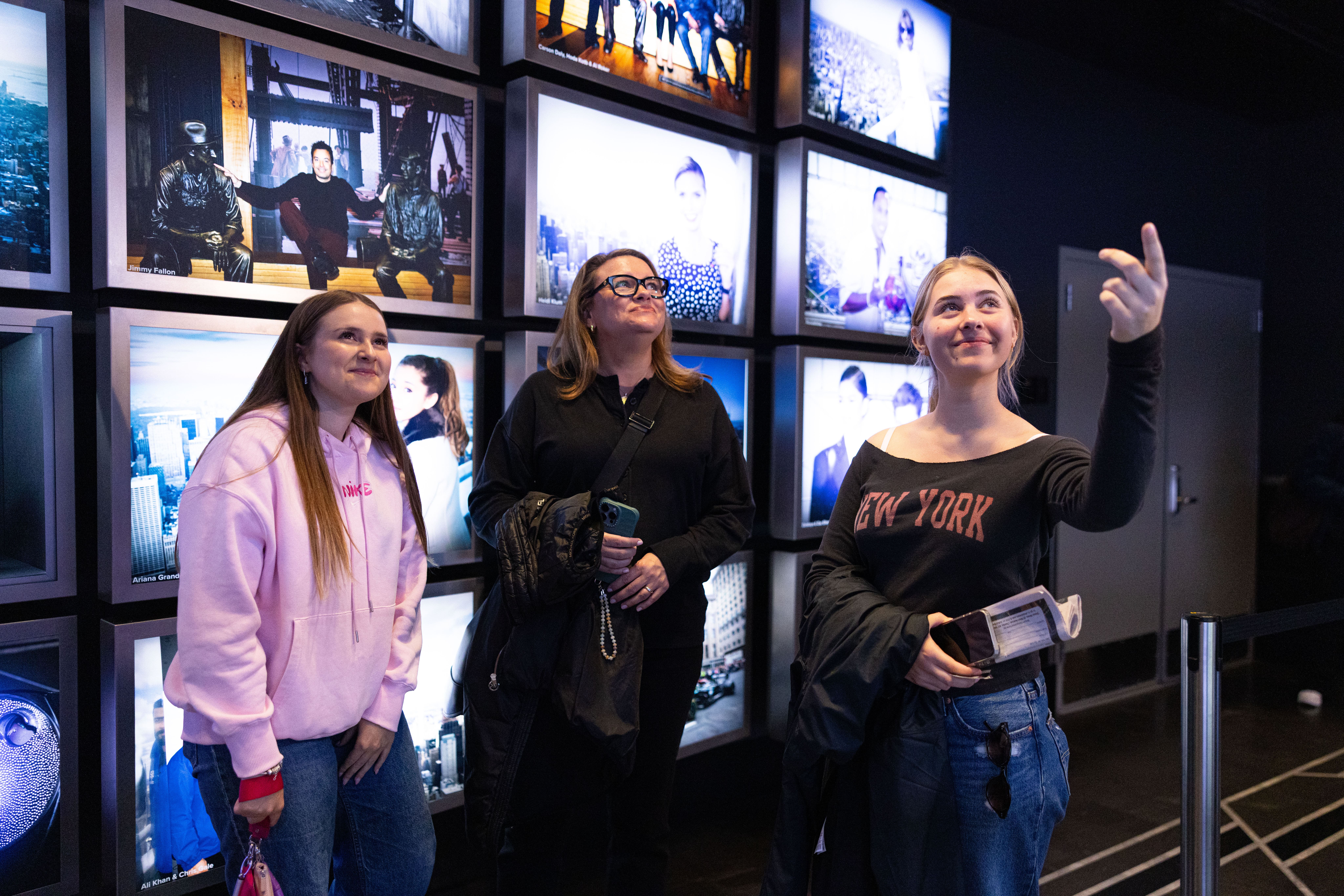 Besucherinnen entdecken die multimediale Ausstellung im Empire State Building mit Fotos prominenter Gäste