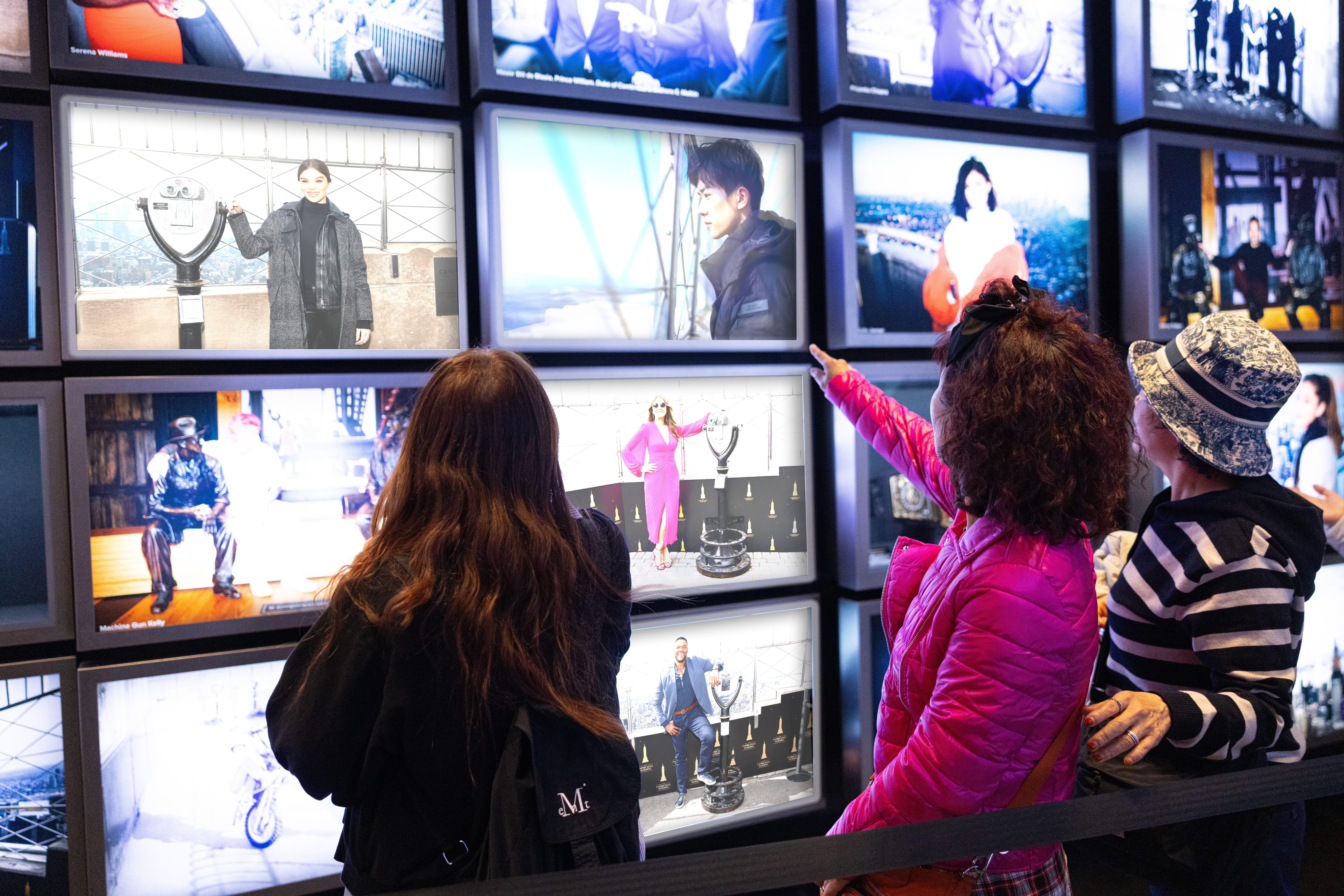 Besucher entdecken eine multimediale Ausstellung mit Fotos und Bildschirmen im Empire State Building in New York.