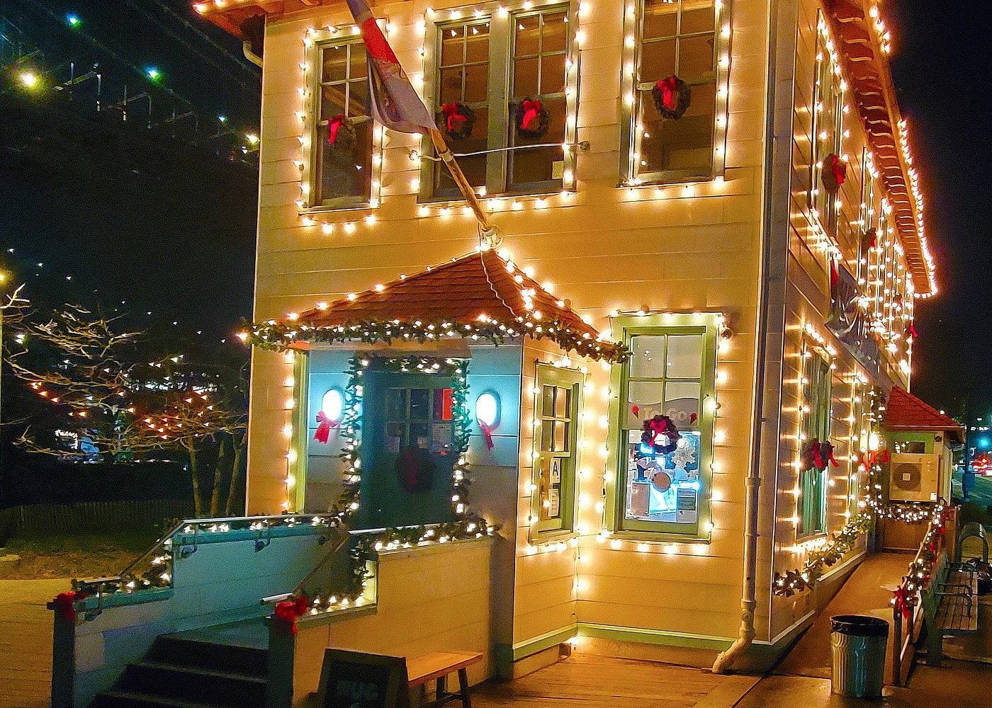Detailansicht eines festlich geschmückten Gebäudes in Brooklyn mit Weihnachtslichtern und roten Schleifen.