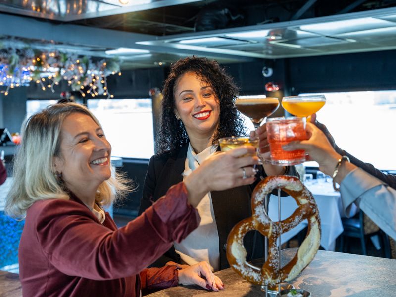 Gäste stoßen mit farbenfrohen Cocktails an einer Bar auf einem Ausflugsschiff an.