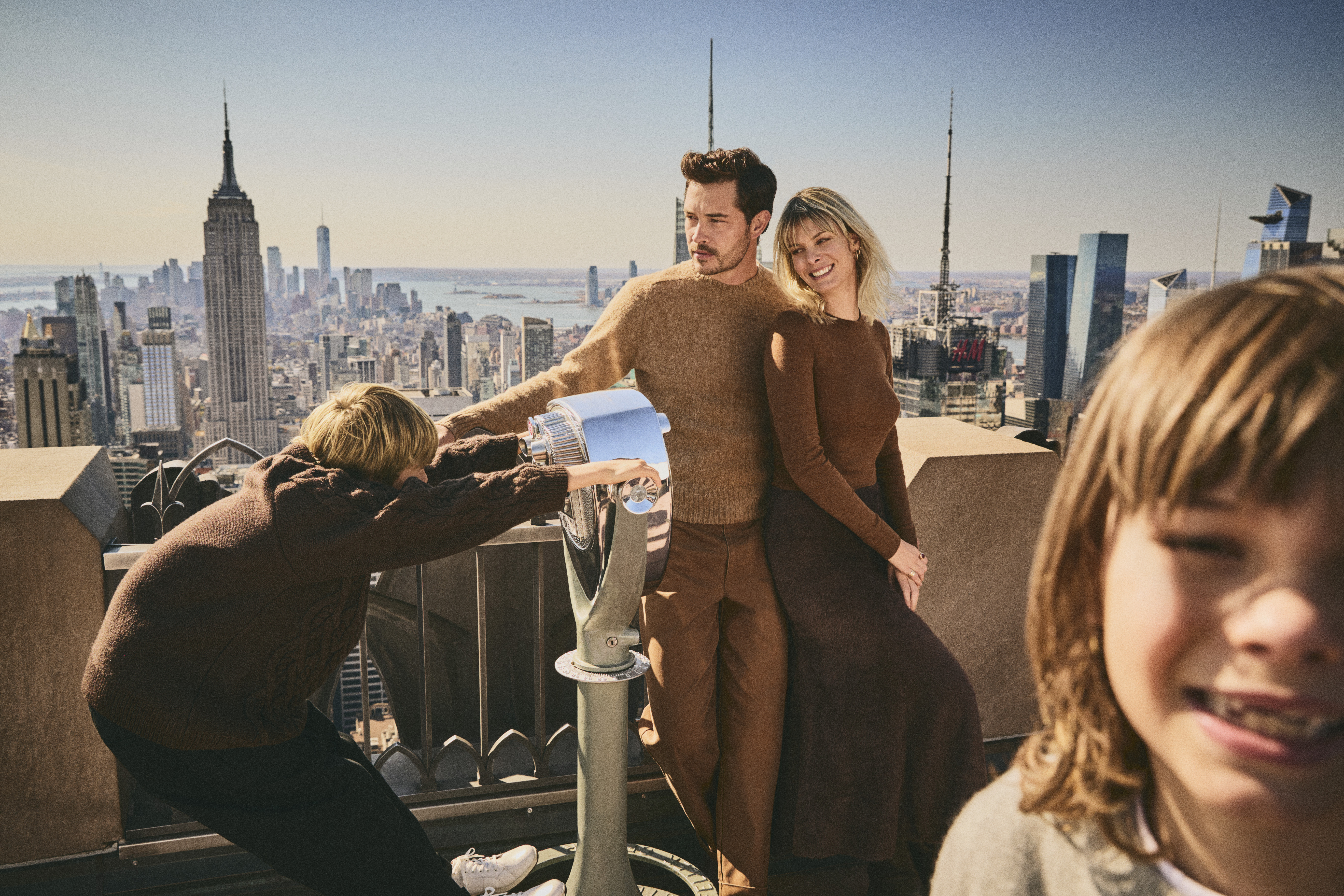Familie auf der Top of the Rock Aussichtsplattform mit dem Empire State Building und der Skyline von New York im Hintergrund