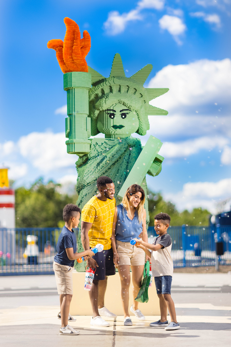 Familie vor einer riesigen aus LEGO Steinen gestalteten Freiheitsstatue im LEGOLAND New York Resort