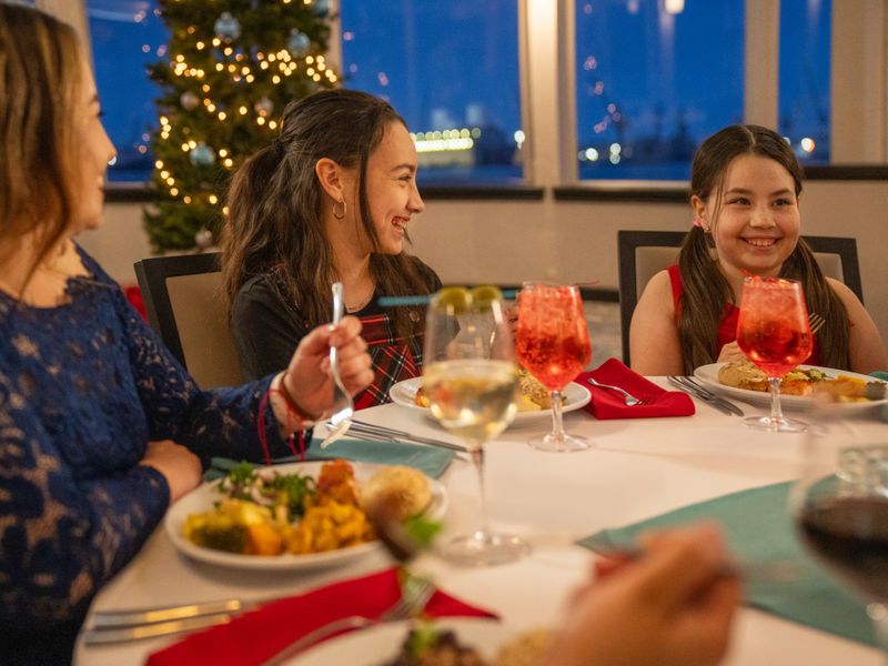 Familie genießt ein festliches Abendessen mit Getränken an einem gedeckten Tisch auf einem Ausflugsschiff in New York.