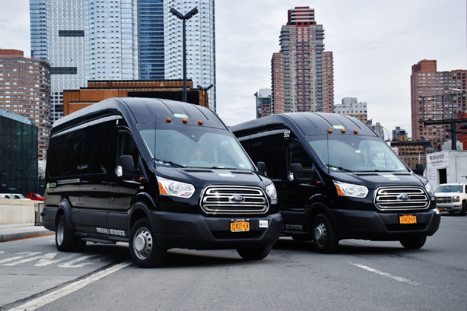 Zwei schwarze GO Airlink Transporter nebeneinander auf einer Straße mit Manhattan-Skyline im Hintergrund