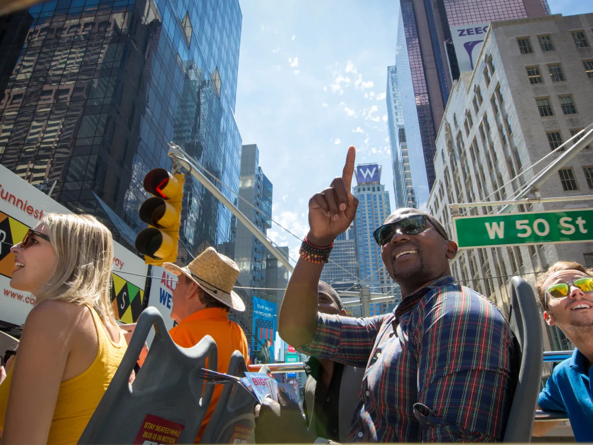 Tourist zeigt vom offenen Oberdeck des Big Bus auf ein Hochhaus in Times Square, New York