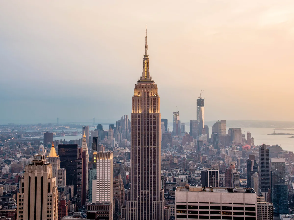 Das Empire State Building ragt bei Abenddämmerung im Zentrum der Skyline von Manhattan empor.