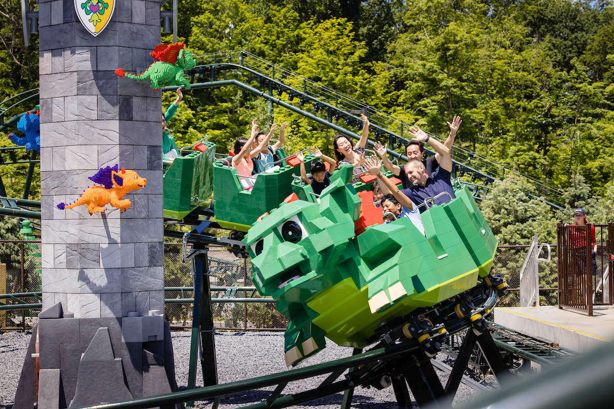 Familien fahren in einer grünen Drachen-Achterbahn durch den LEGOLAND New York Freizeitpark