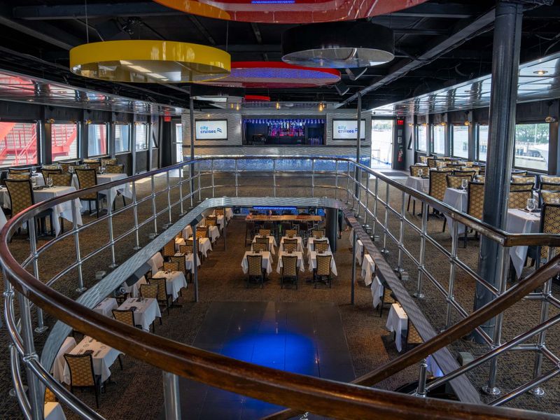 Zweistöckiger, festlich eingerichteter Speisesaal der Dinner Cruise mit gedeckten Tischen und Bühne im Hintergrund