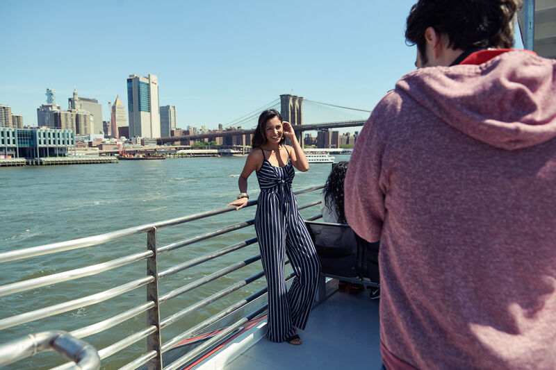 Passagiere auf einer Circle Line Bootstour mit Blick auf die Brooklyn Bridge und die Skyline von Manhattan.