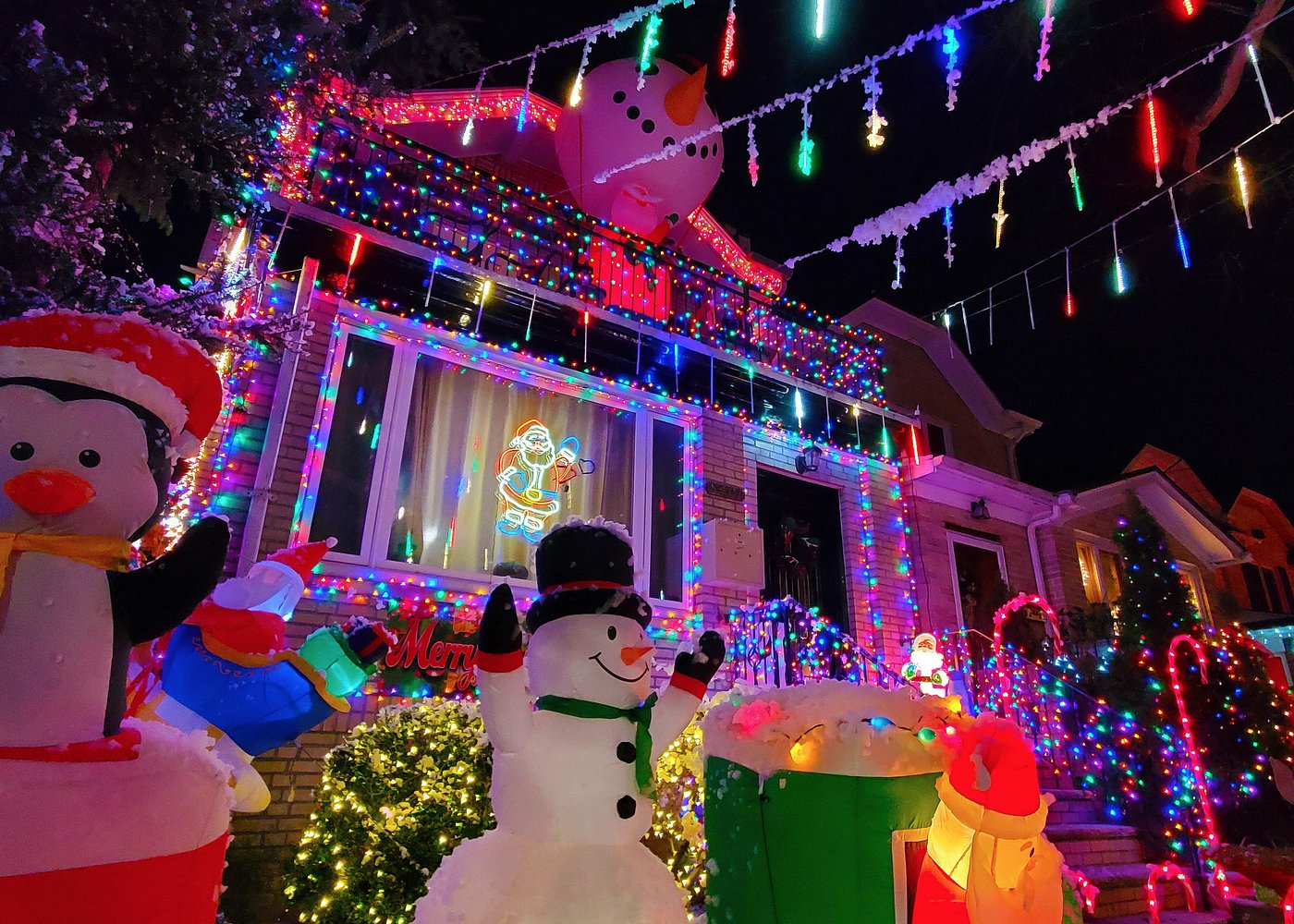 Aufwendig beleuchtetes Wohnhaus in Brooklyn mit bunten Lichterketten, Schneemännern und Weihnachtsfiguren.