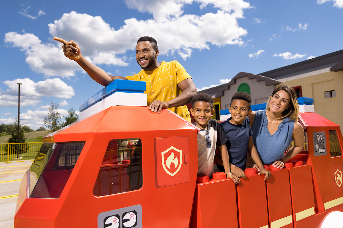Familie an einem roten LEGO Feuerwehrfahrzeug in einem Themenbereich des LEGOLAND New York Resort