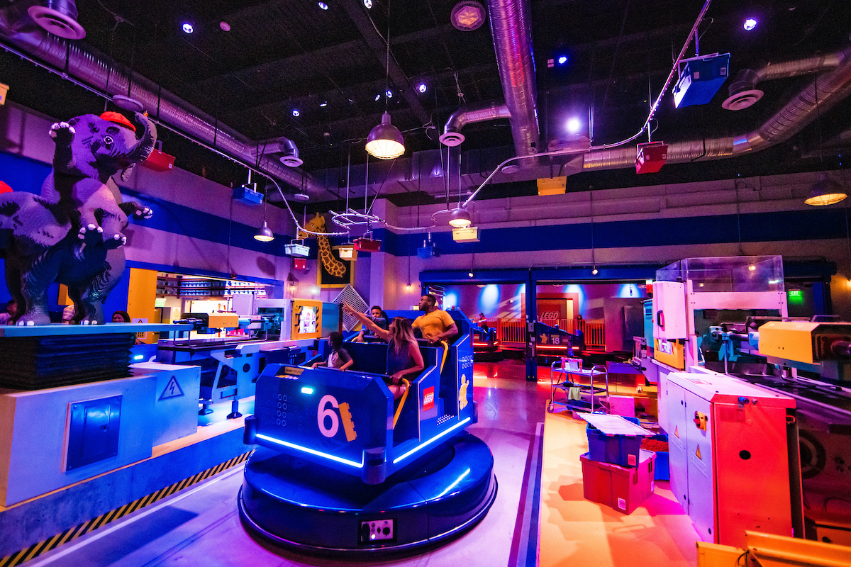 Besucher in einem interaktiven Indoor-Fahrgeschäft mit LEGO Figuren im LEGOLAND New York Resort