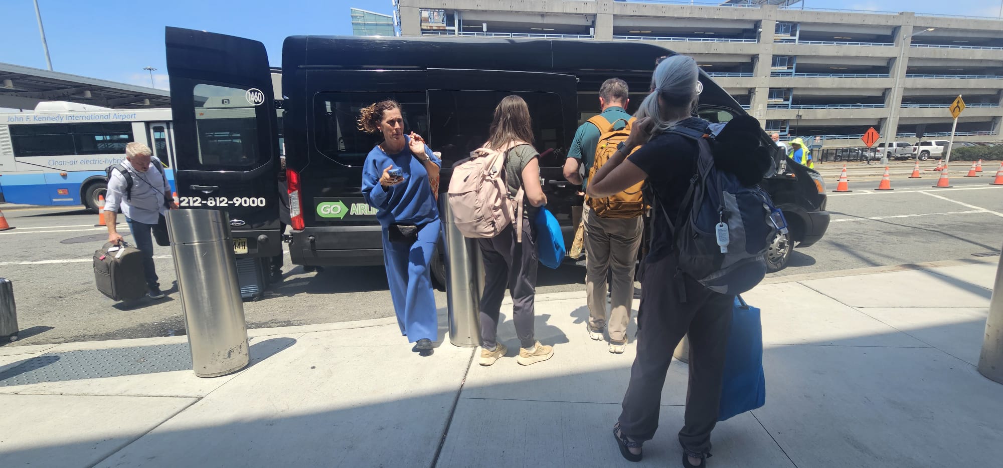 Reisende mit Gepäck und Rucksäcken steigen am JFK Airport in einen schwarzen GO Airlink Shuttle-Van