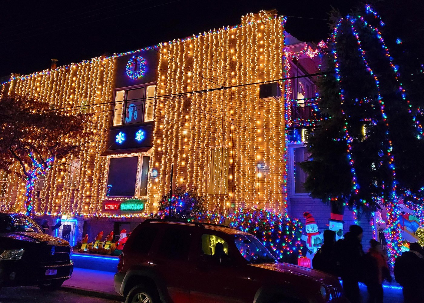 Wohnhaus in Brooklyn mit dicht angebrachten goldenen Lichterketten und farbenfroher Weihnachtsbeleuchtung.
