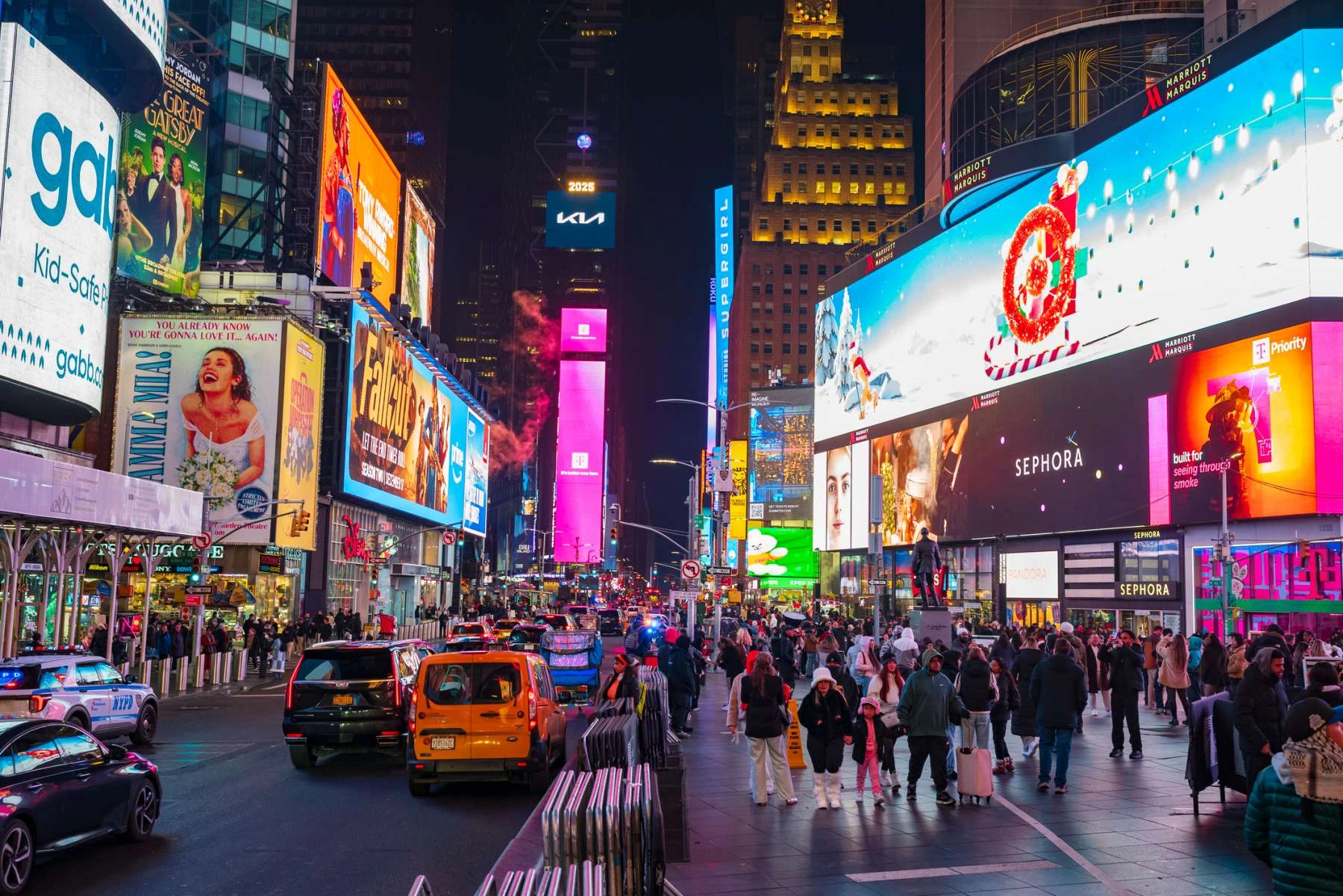 Belebter Times Square in New York bei Nacht mit bunten Leuchtreklamen, Verkehr und zahlreichen Fußgängern