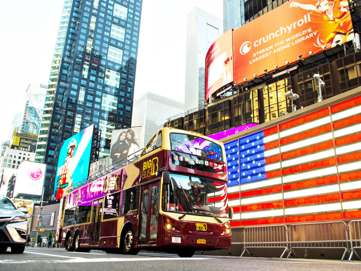 Big-Bus-New-York-Doppeldeckerbus fährt abends durch die beleuchtete Times Square