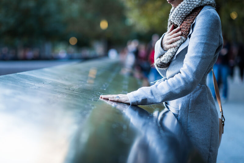 Besucherin an einem Gedenkbecken des 9/11 Memorial in New York mit eingravierten Namen der Opfer.