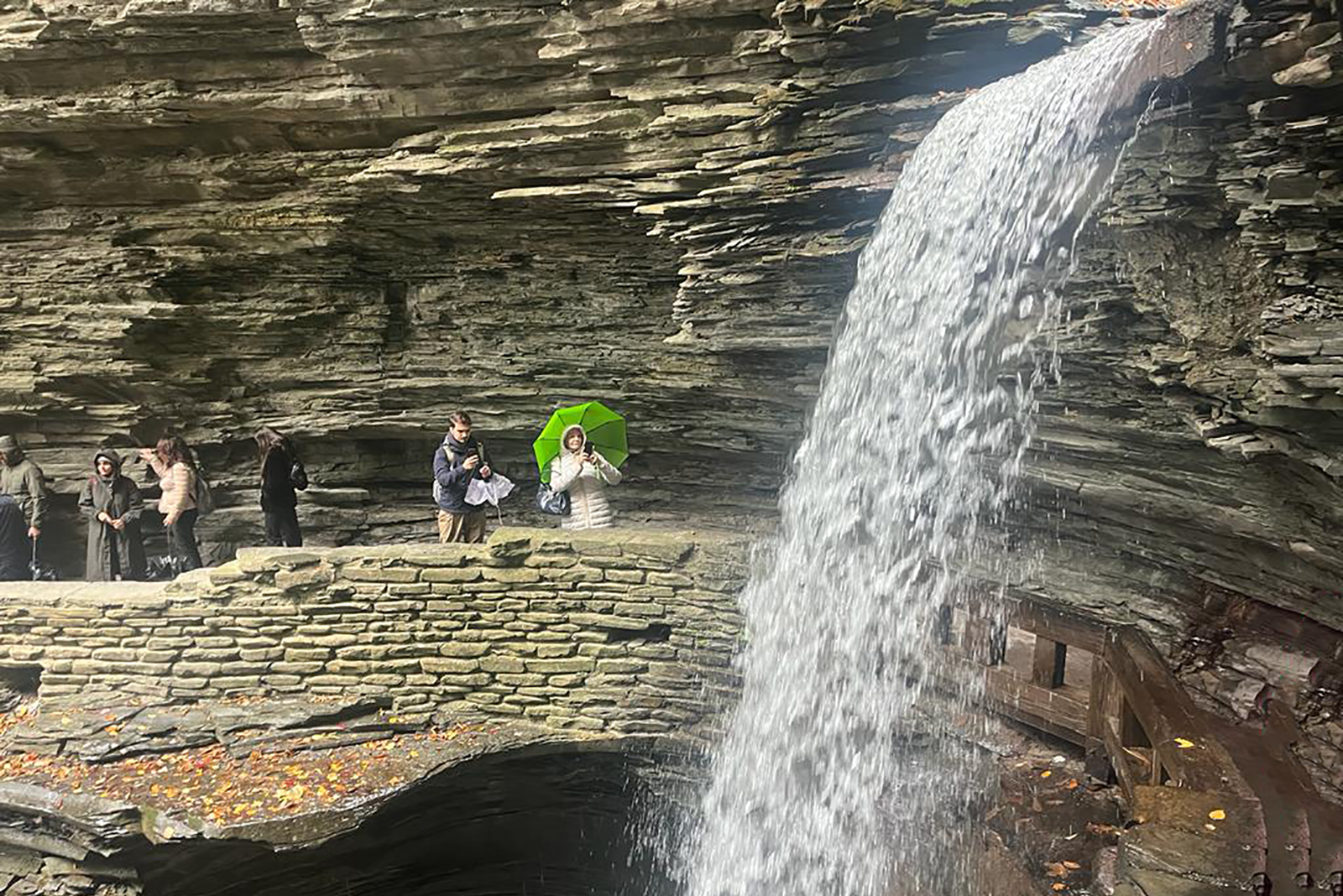 Besucher an einem Wasserfall zwischen den Felswänden des Watkins Glen State Park