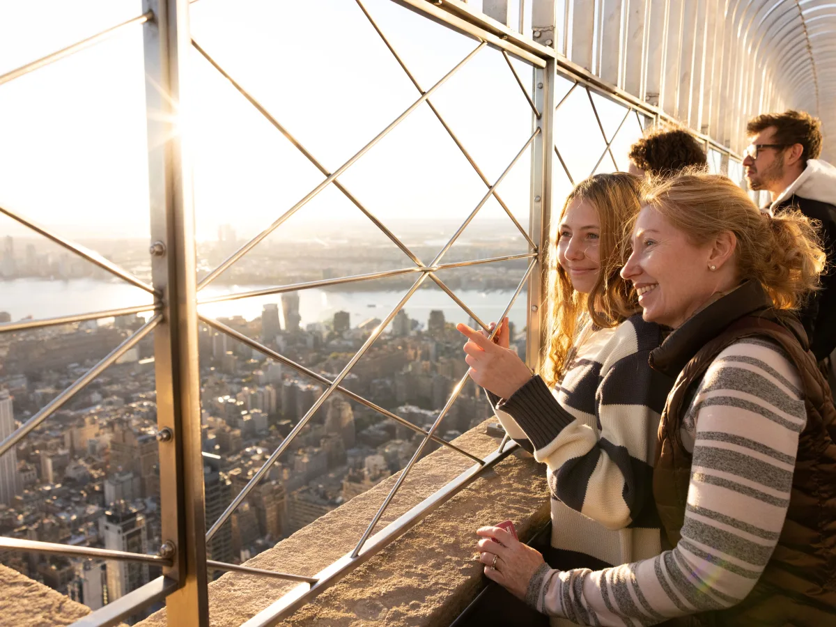 Zwei Frauen genießen im Sonnenuntergang die Aussicht auf Manhattan von der 86. Etage des Empire State Buildings.