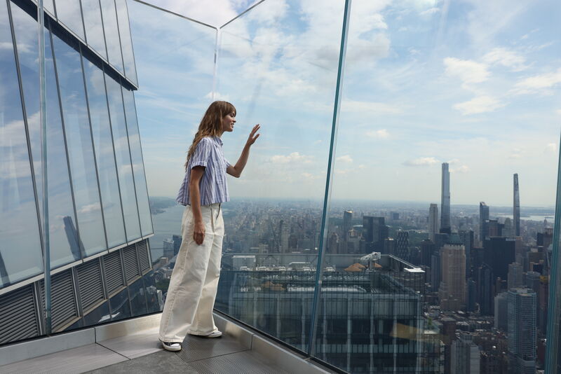 Besucherin auf der gläsernen Aussichtsplattform Edge NYC mit Panoramablick über Manhattan.