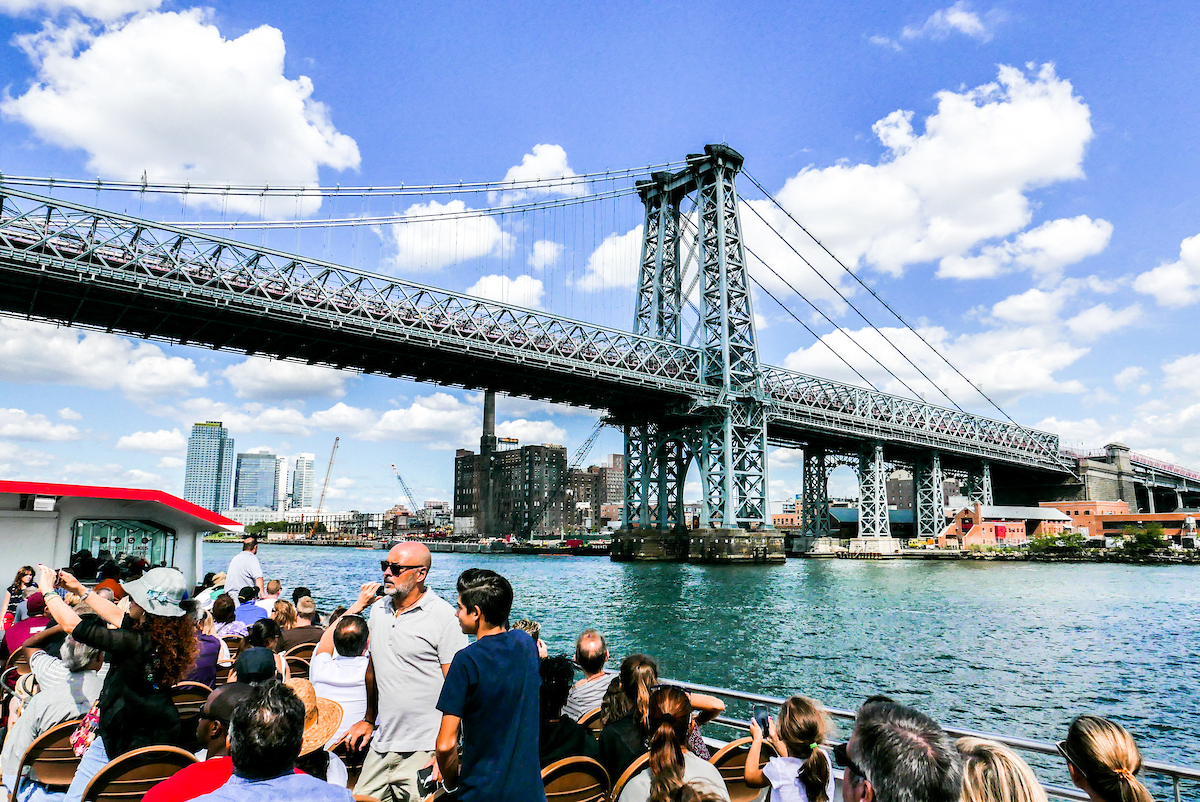 Passagiere auf einer Bootstour vor der Williamsburg Bridge am East River