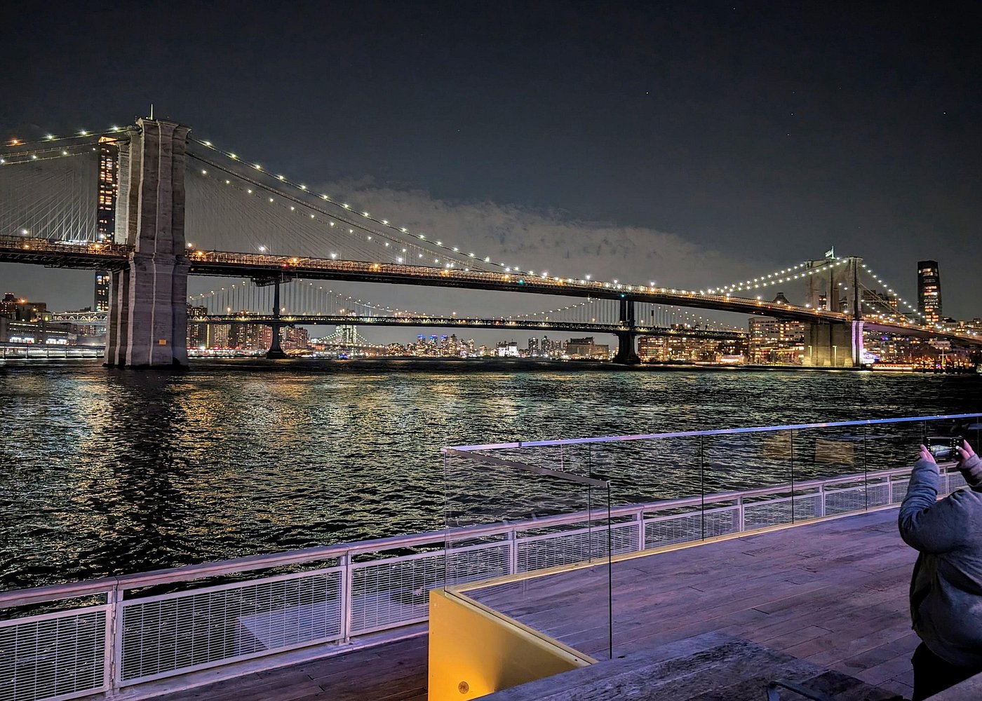 Blick auf die beleuchtete Brooklyn Bridge und die Manhattan Bridge über dem East River bei Nacht.