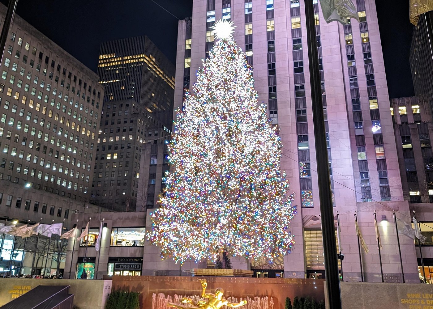 Riesiger, mit Tausenden bunten Lichtern geschmückter Weihnachtsbaum am Rockefeller Center in Manhattan bei Nacht.