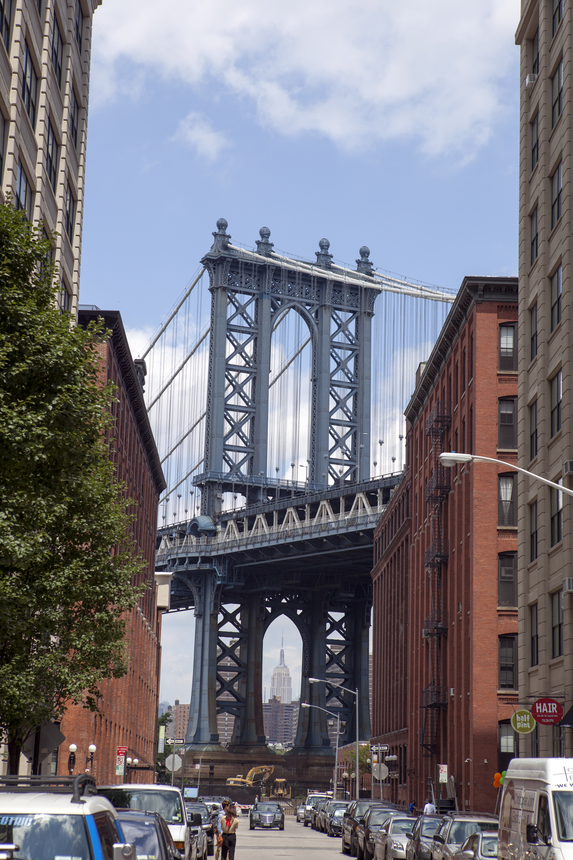 Blick durch eine Straßenschlucht in DUMBO auf die massive Architektur der Manhattan Bridge in New York City.
