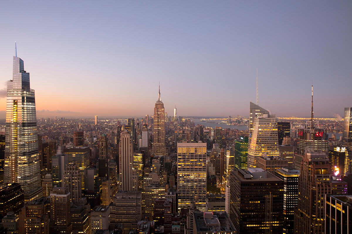 Panoramablick vom Top of the Rock auf das Empire State Building und die beleuchtete Skyline von Manhattan in der Abenddämmerung