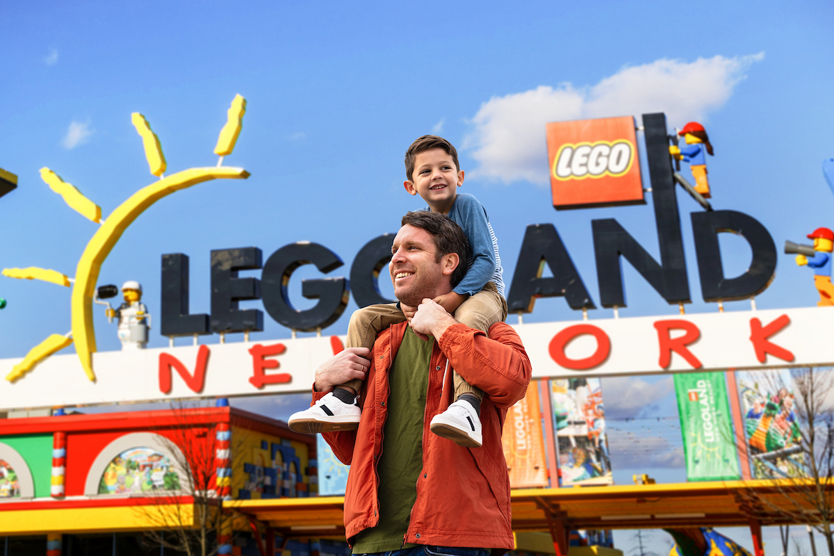 Vater mit Kind auf den Schultern vor dem großen LEGOLAND New York Eingangsschild