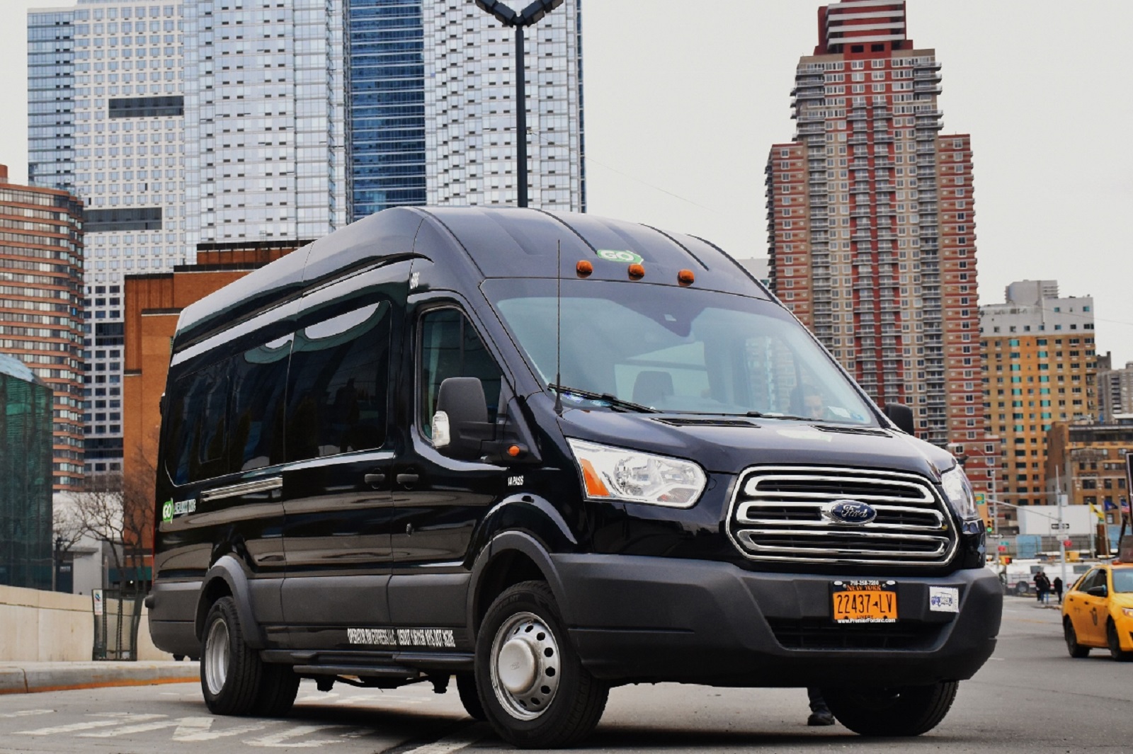 Frontansicht eines schwarzen GO Airlink Ford Transit Shuttles vor der New Yorker Skyline