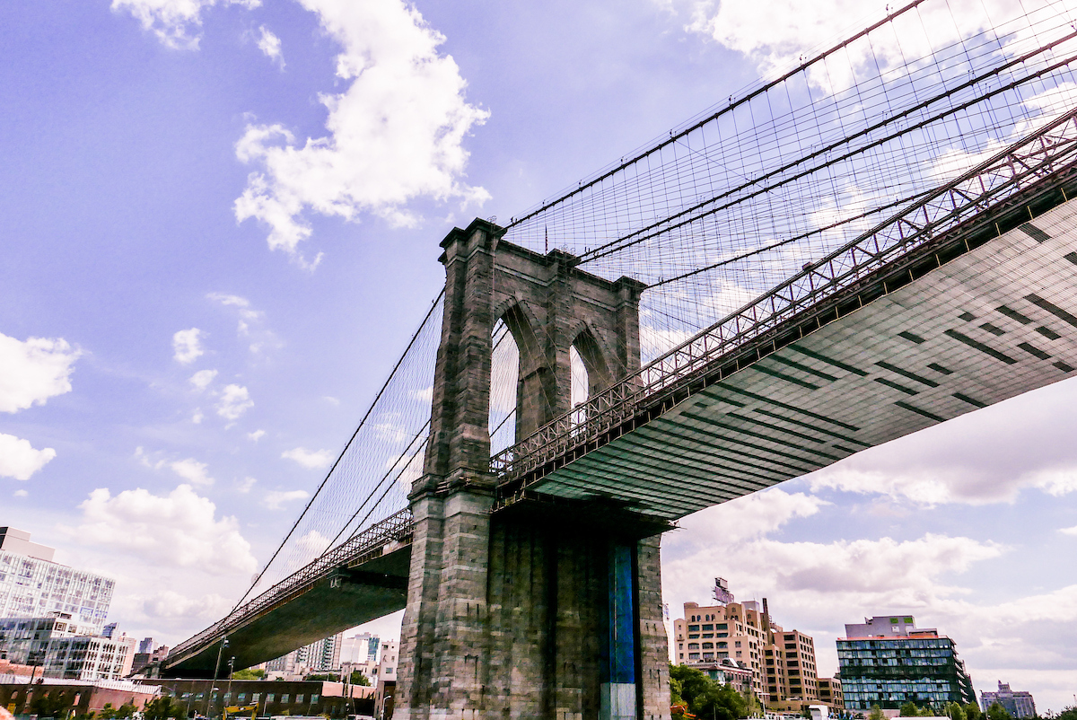 Untersicht der Brooklyn Bridge mit Steinpfeilern und Stahlseilen