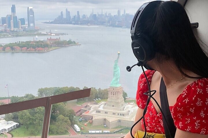 Passagierin blickt während eines Helikopterflugs auf die Freiheitsstatue und die Skyline von Manhattan