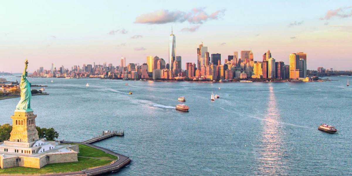 Luftaufnahme der Freiheitsstatue und der Skyline von Manhattan bei Sonnenuntergang
