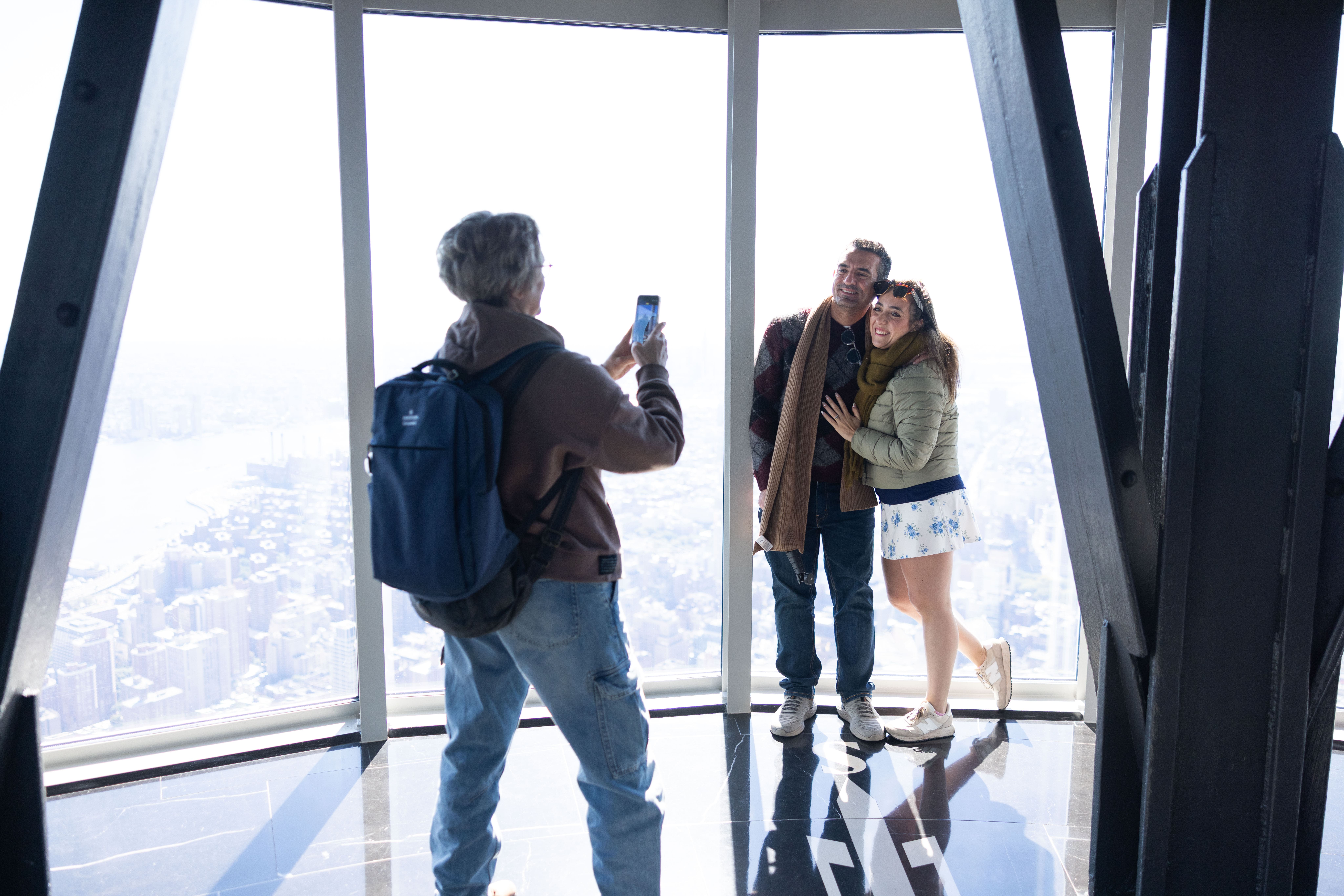 Besucher lassen sich vor den großen Panoramafenstern des Empire State Buildings mit Blick über New York fotografieren.